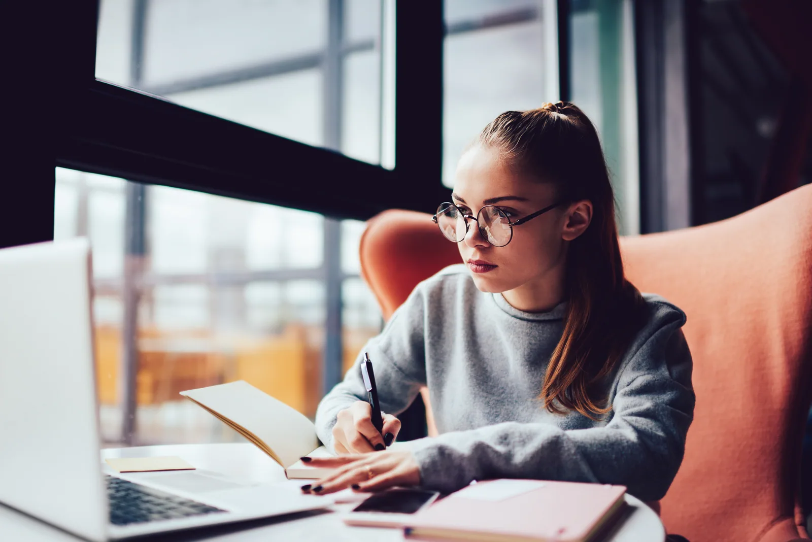 An A-Level student making notes while studying online
