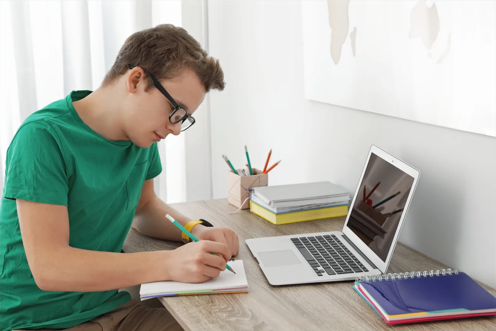 A student writing notes while studying online