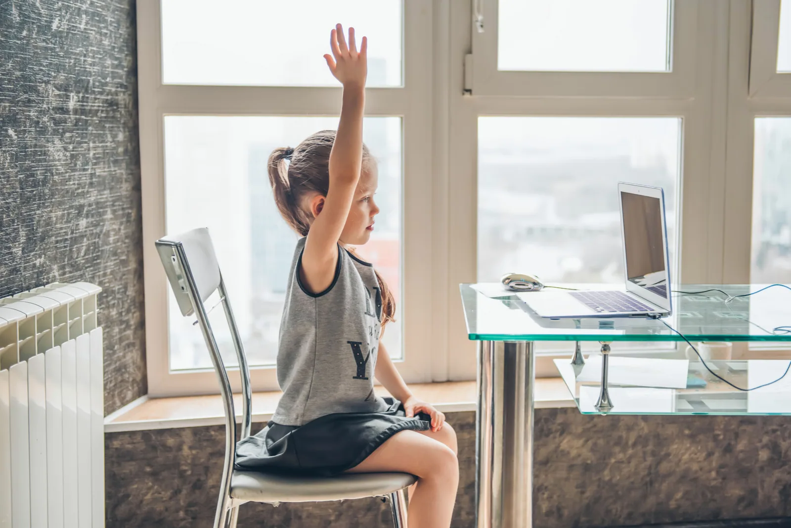 A school-age learner raising her hand during an online lesson